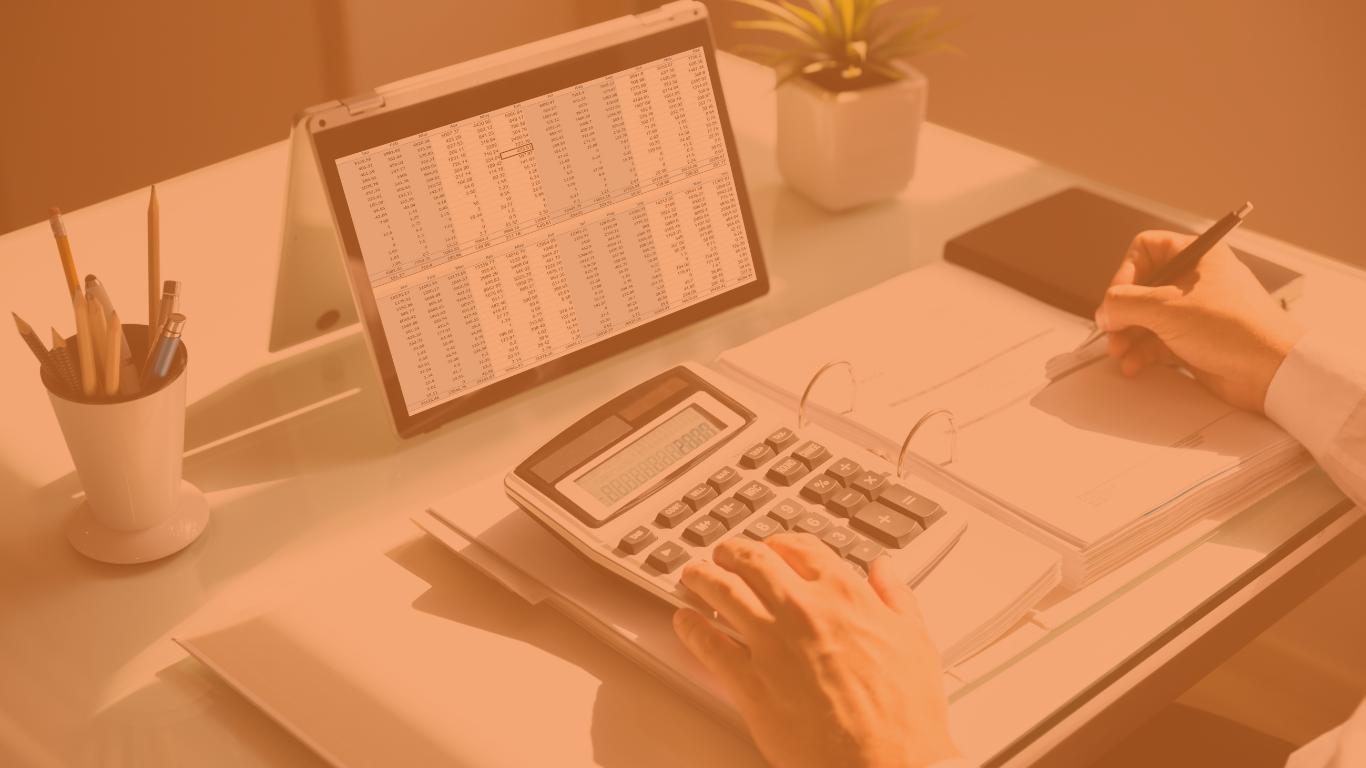 Person working on invoices at a desk, with papers, a laptop, and a calculator visible.