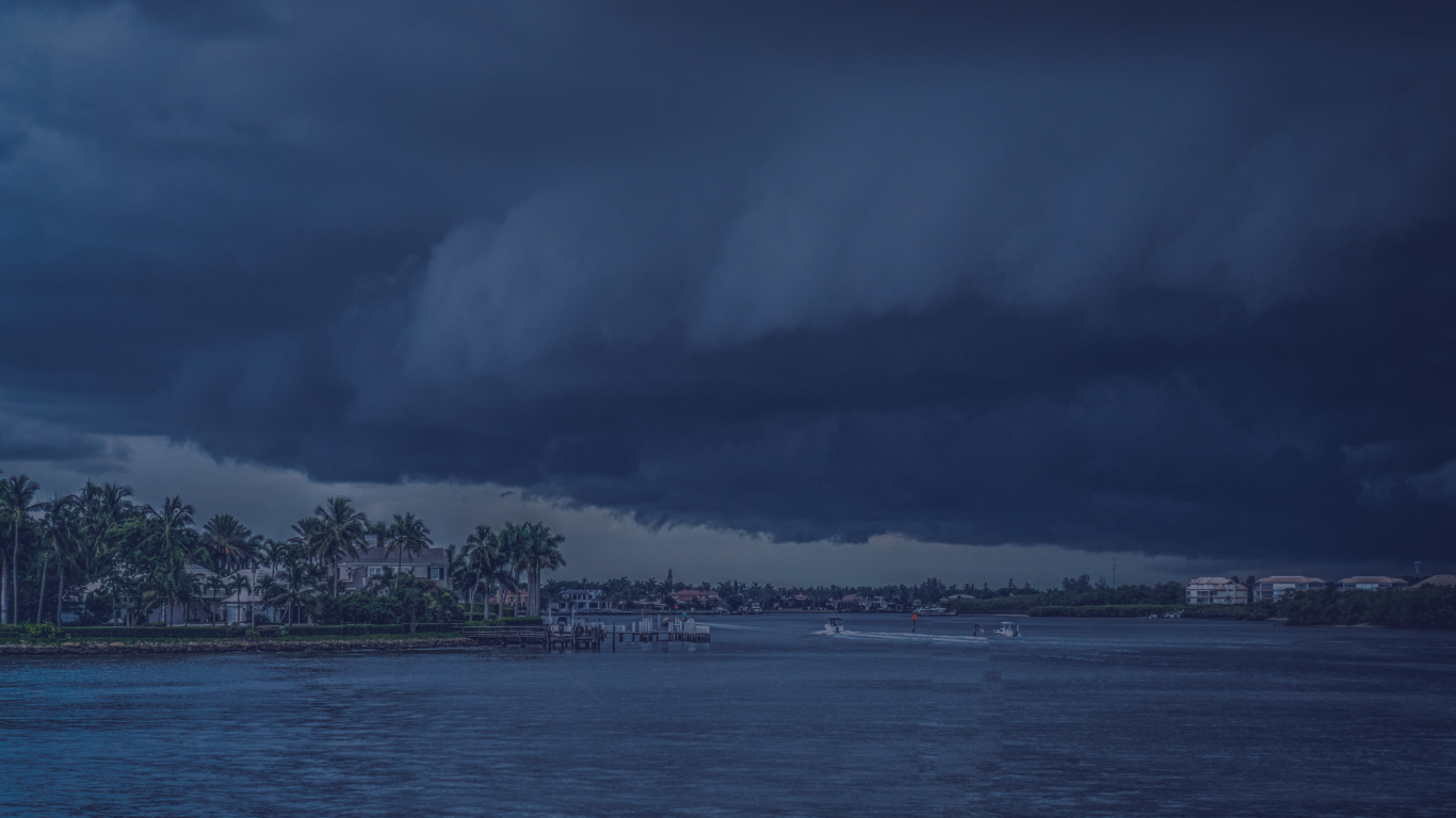 Dark storm clouds moving over a body of water, signaling the need for hurricane season preparation. approaching hurricane