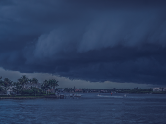 Dark storm clouds moving over a body of water, signaling the need for hurricane season preparation. approaching hurricane