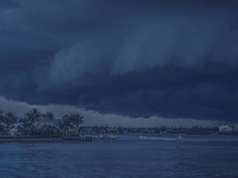 Dark storm clouds moving over a body of water, signaling the need for hurricane season preparation. approaching hurricane