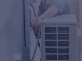 A maintenance technician checking an AC unit inside an apartment during summer