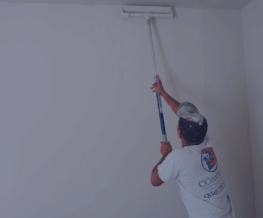 Man painting an apartment wall with roller.
